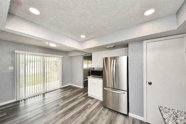 kitchen with stainless steel appliances, baseboards, white cabinetry, wood finished floors, and visible vents