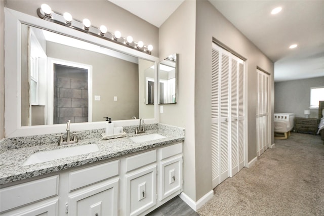 bathroom featuring double vanity, a sink, baseboards, and recessed lighting