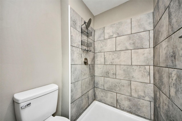 full bathroom with a tile shower and toilet