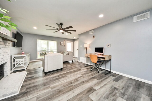 office featuring ceiling fan, a fireplace, recessed lighting, wood finished floors, and visible vents