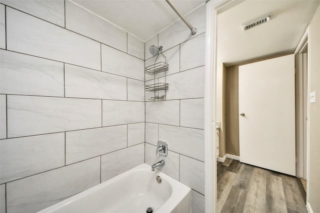 bathroom with shower / bath combination, wood finished floors, and visible vents