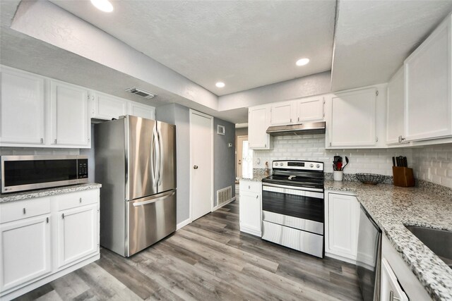 kitchen featuring under cabinet range hood, stainless steel appliances, white cabinetry, and visible vents