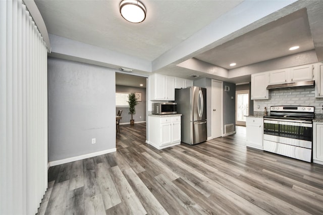 kitchen featuring stainless steel appliances, baseboards, white cabinets, under cabinet range hood, and a tray ceiling