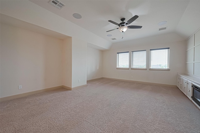 empty room with light colored carpet, ceiling fan, vaulted ceiling, and visible vents