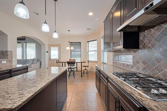 kitchen with visible vents, stainless steel gas cooktop, under cabinet range hood, light stone counters, and light tile patterned floors