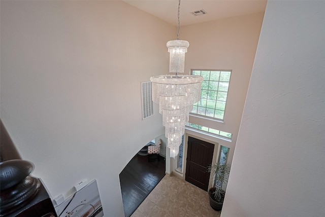 entryway featuring a towering ceiling, visible vents, and a chandelier