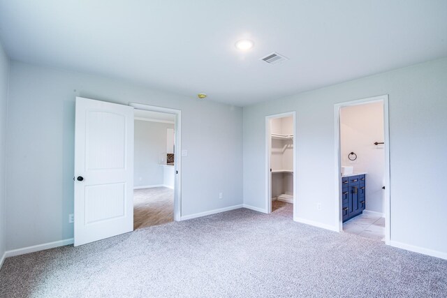6714 Scott St, Liverpool, TX 77577 - unfurnished bedroom with connected bathroom, a spacious closet, visible vents, light carpet, and baseboards