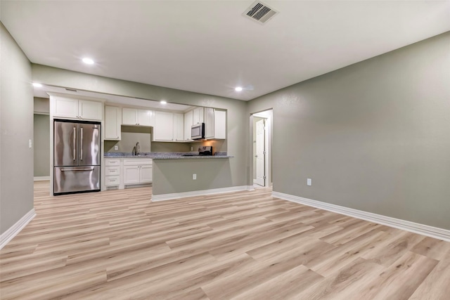 kitchen featuring baseboards, a sink, light wood-style floors, and appliances with stainless steel finishes