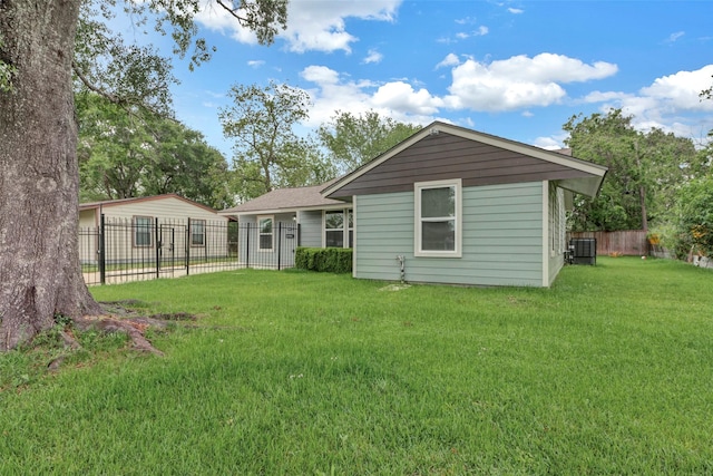 back of property with fence, central air condition unit, and a yard