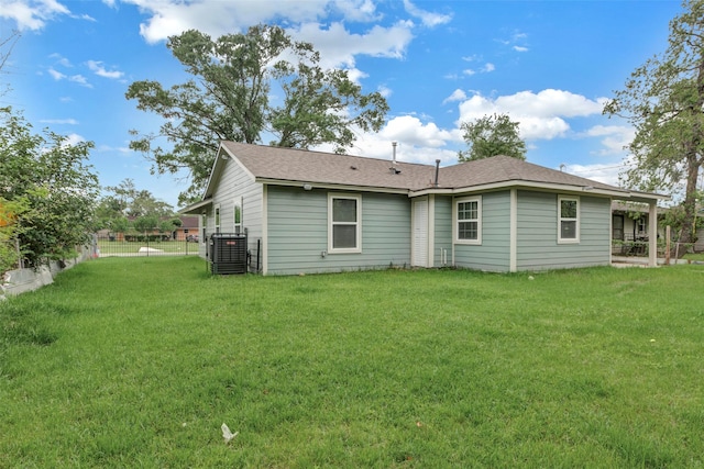 rear view of property featuring a shingled roof, cooling unit, fence, and a yard