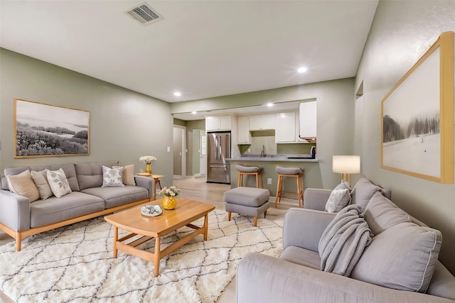 living room with visible vents, light wood-style flooring, and recessed lighting