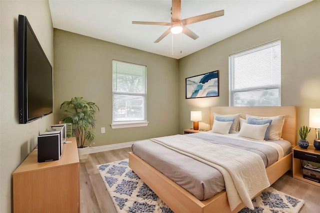 bedroom featuring baseboards, light wood finished floors, and ceiling fan