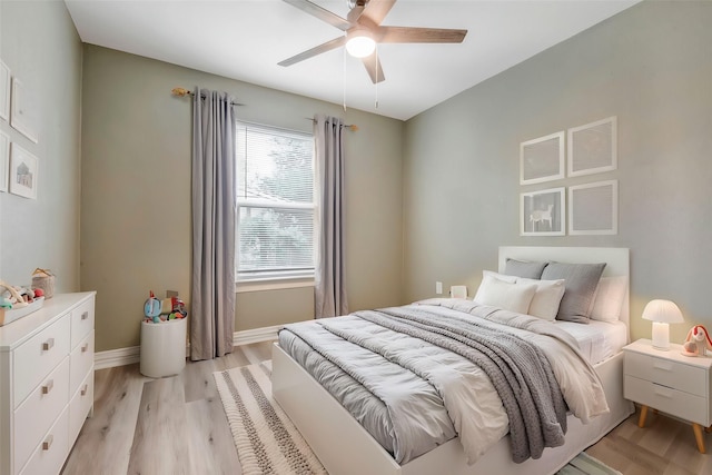 bedroom with baseboards, light wood-style floors, and a ceiling fan