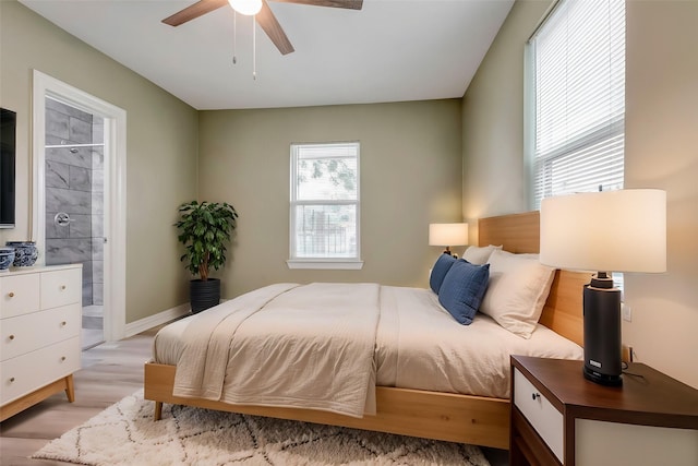 bedroom with connected bathroom, baseboards, light wood-style flooring, and ceiling fan