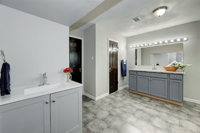 full bath featuring two vanities, a sink, baseboards, and visible vents