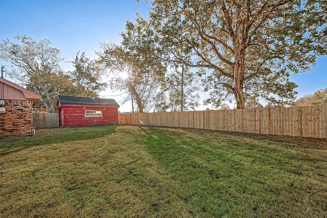 view of yard with a storage unit, a fenced backyard, and an outbuilding