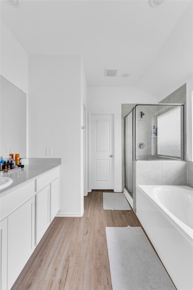 bathroom featuring vaulted ceiling, visible vents, wood finished floors, a shower stall, and vanity