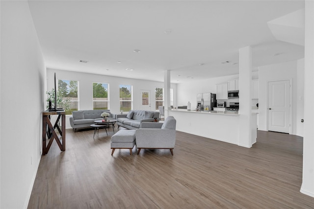 living room with visible vents, baseboards, and wood finished floors
