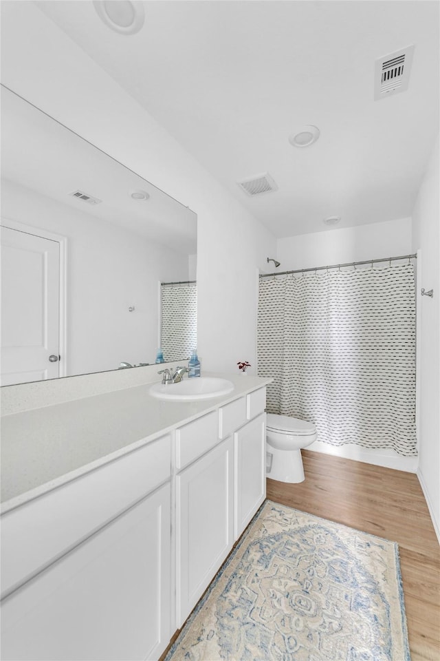 full bathroom featuring curtained shower, wood finished floors, visible vents, toilet, and vanity