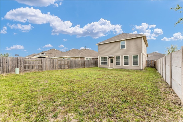 rear view of property with a fenced backyard and a yard