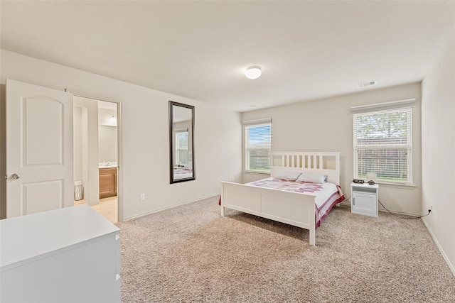 carpeted bedroom with baseboards, visible vents, and ensuite bathroom