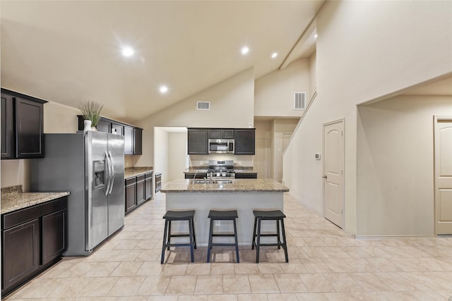 kitchen with a kitchen island with sink, visible vents, light stone countertops, and stainless steel appliances