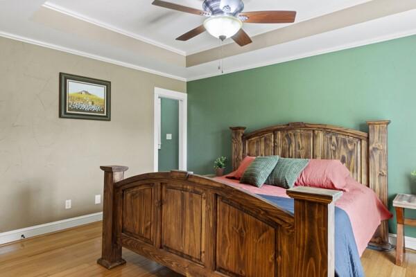 1760 County Road 965, Alvin, TX 77511 - bedroom with light wood-style floors, a tray ceiling, crown molding, ceiling fan, and baseboards