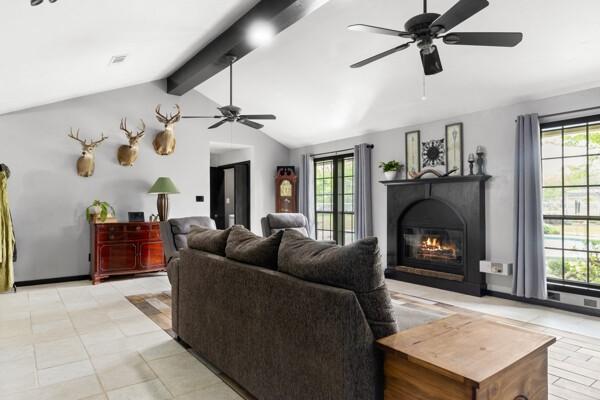 1760 County Road 965, Alvin, TX 77511 - living room featuring a ceiling fan, healthy amount of natural light, a glass covered fireplace, and light tile patterned floors