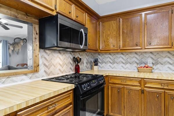 1760 County Road 965, Alvin, TX 77511 - kitchen with black / electric stove, stainless steel microwave, tasteful backsplash, a ceiling fan, and brown cabinetry
