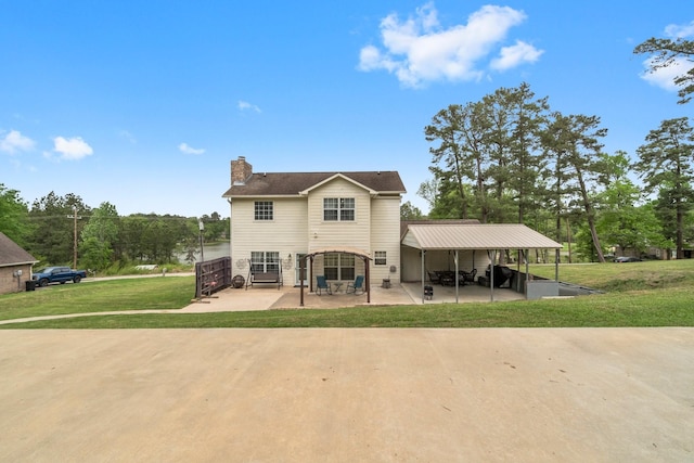 rear view of house featuring a lawn, a chimney, a patio area, and driveway