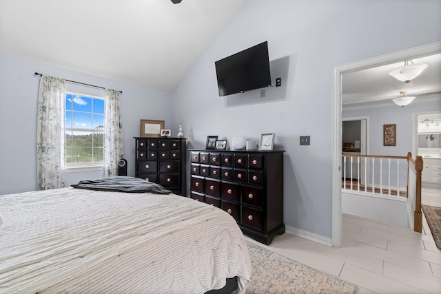 tiled bedroom with baseboards, lofted ceiling, and ensuite bath