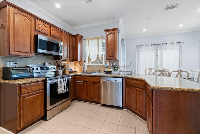 kitchen featuring a sink, appliances with stainless steel finishes, a peninsula, a toaster, and dark stone counters