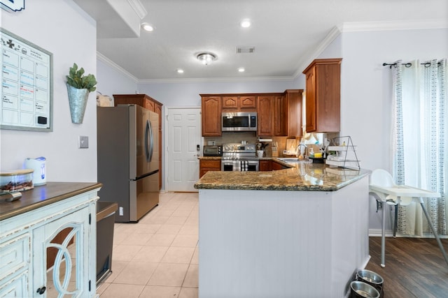 kitchen with visible vents, a peninsula, ornamental molding, stainless steel appliances, and a sink