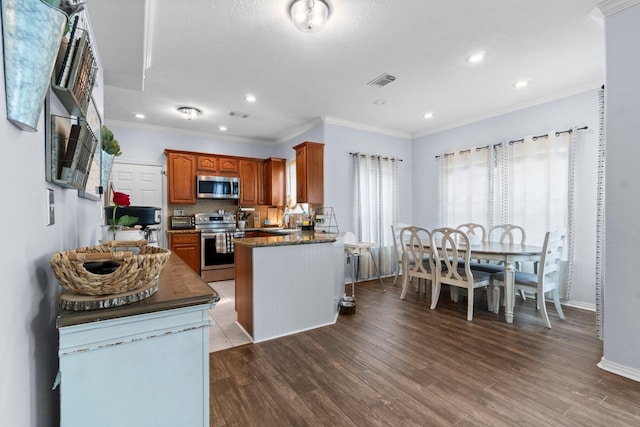 kitchen with visible vents, ornamental molding, stainless steel appliances, dark wood-type flooring, and brown cabinetry