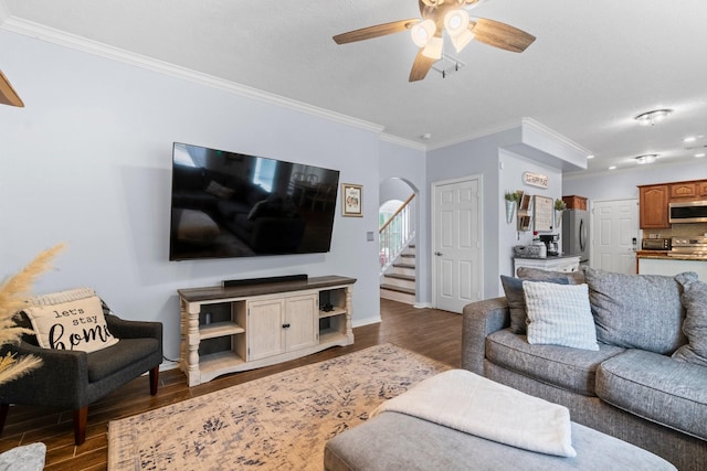 living area with stairs, ornamental molding, arched walkways, a ceiling fan, and wood finished floors