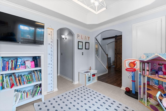 playroom featuring ornamental molding, tile patterned floors, arched walkways, a barn door, and a tray ceiling