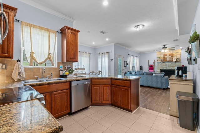 kitchen featuring a sink, visible vents, dishwasher, a peninsula, and brown cabinets