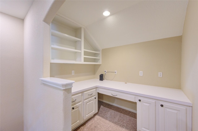 unfurnished office with light carpet, built in study area, and vaulted ceiling