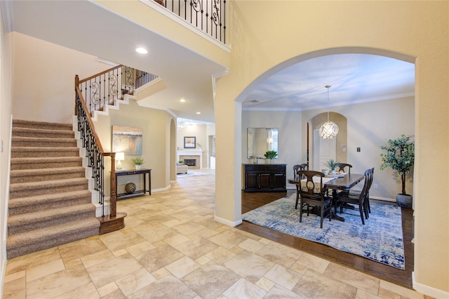 dining space with arched walkways, a towering ceiling, ornamental molding, stairs, and baseboards