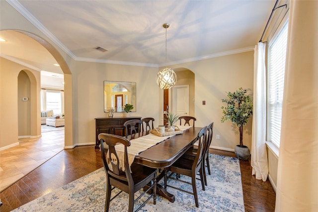 dining space featuring arched walkways, wood finished floors, ornamental molding, and visible vents