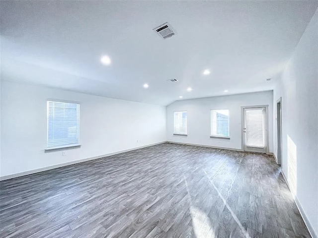unfurnished room featuring baseboards, visible vents, wood finished floors, and lofted ceiling
