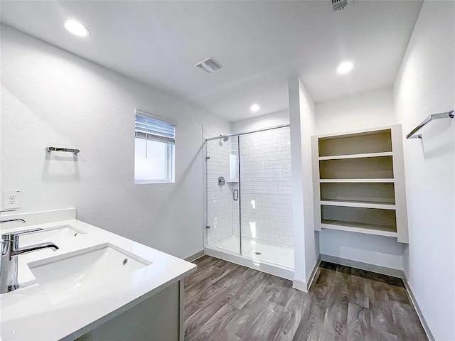 full bath featuring baseboards, a sink, a stall shower, visible vents, and wood finished floors
