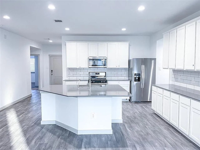 kitchen with white cabinetry, light wood-style flooring, a center island with sink, and appliances with stainless steel finishes