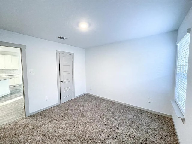unfurnished bedroom featuring baseboards, visible vents, and carpet