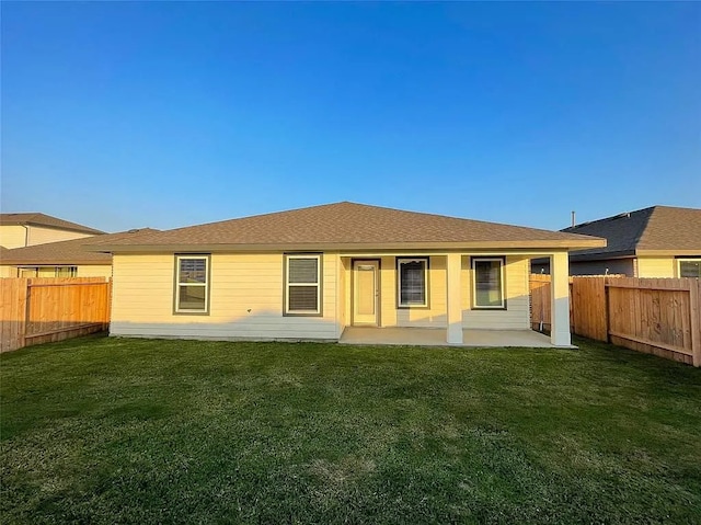 rear view of house featuring a fenced backyard, a lawn, and a patio