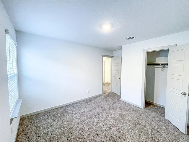 unfurnished bedroom featuring baseboards, carpet floors, visible vents, and a closet