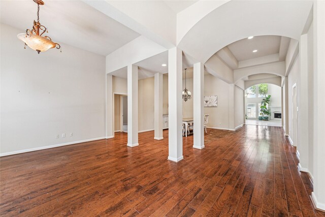 2230 Dali Ln, Missouri City, TX 77459 - foyer featuring arched walkways, a fireplace with raised hearth, dark wood-style flooring, and baseboards