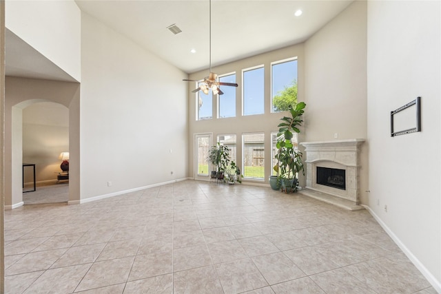 2230 Dali Ln, Missouri City, TX 77459 - unfurnished living room featuring ceiling fan, a fireplace, arched walkways, light tile patterned flooring, and baseboards
