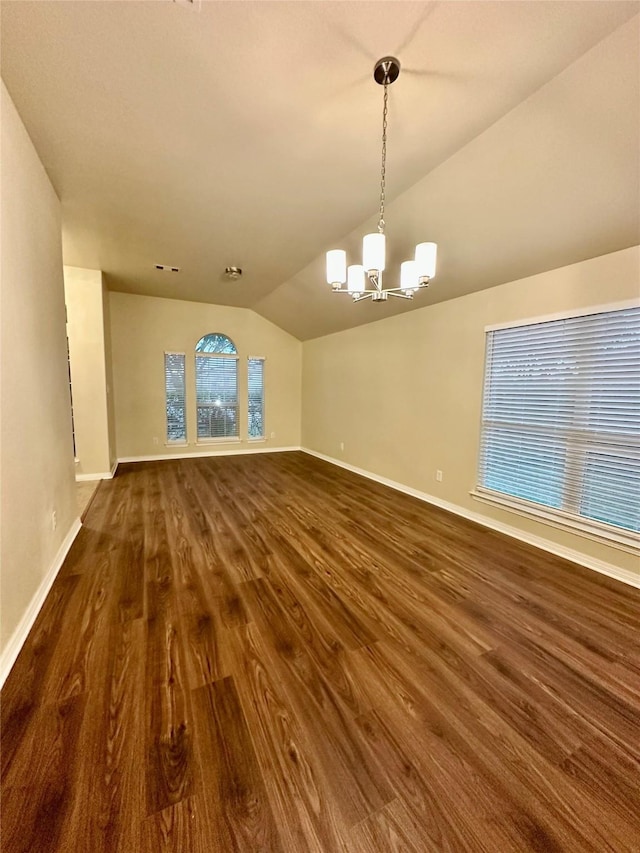 empty room featuring dark wood-type flooring, baseboards, vaulted ceiling, and a notable chandelier
