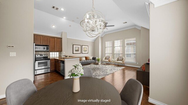 dining space with a notable chandelier, crown molding, vaulted ceiling, visible vents, and dark wood-type flooring